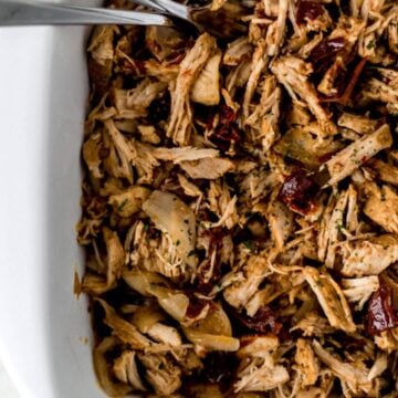 close up view of pulled pork in white baking dish with forks