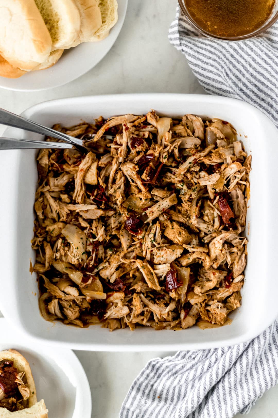 pulled pork in square white baking dish with forks in it