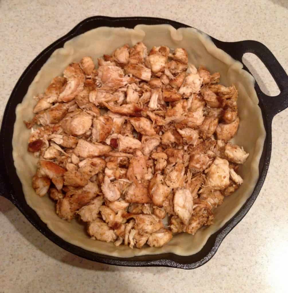Overhead view of chicken over pie crust in skillet for Easy Chicken Pot Pie 