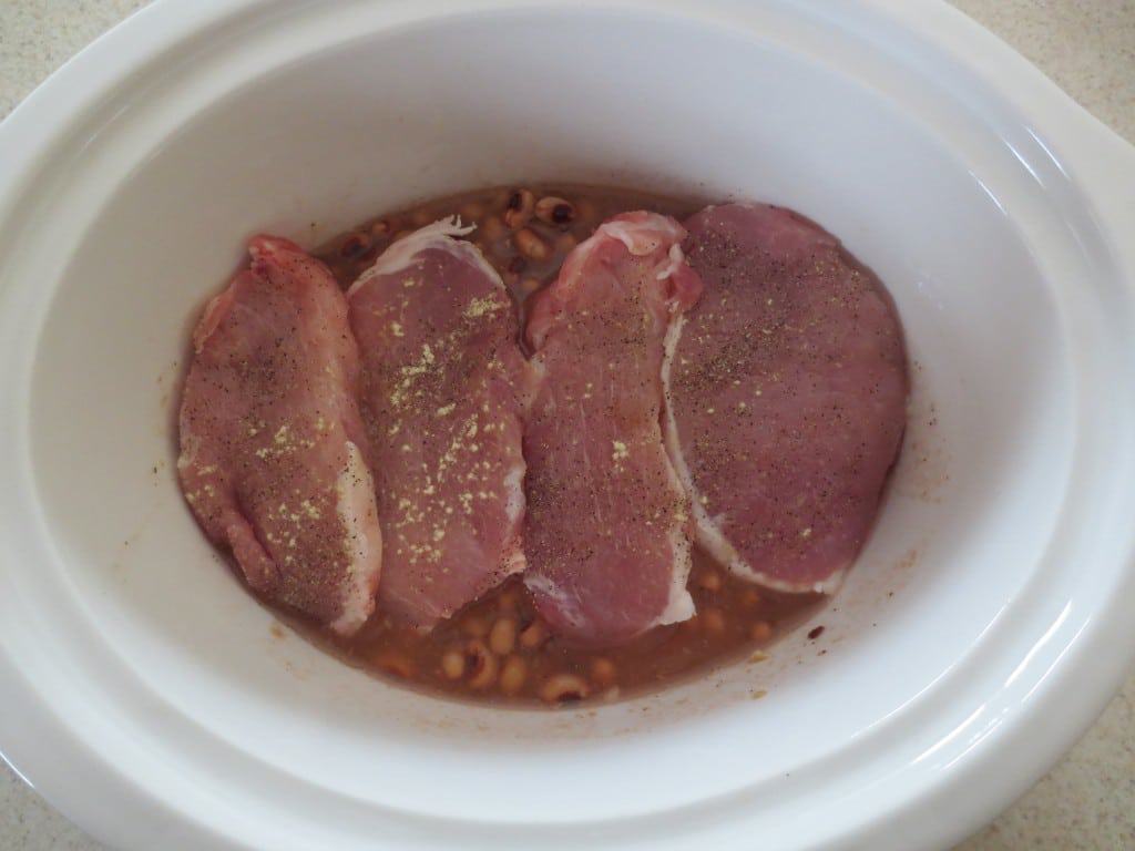 slow cooker with black eyed peas topped with pork chops