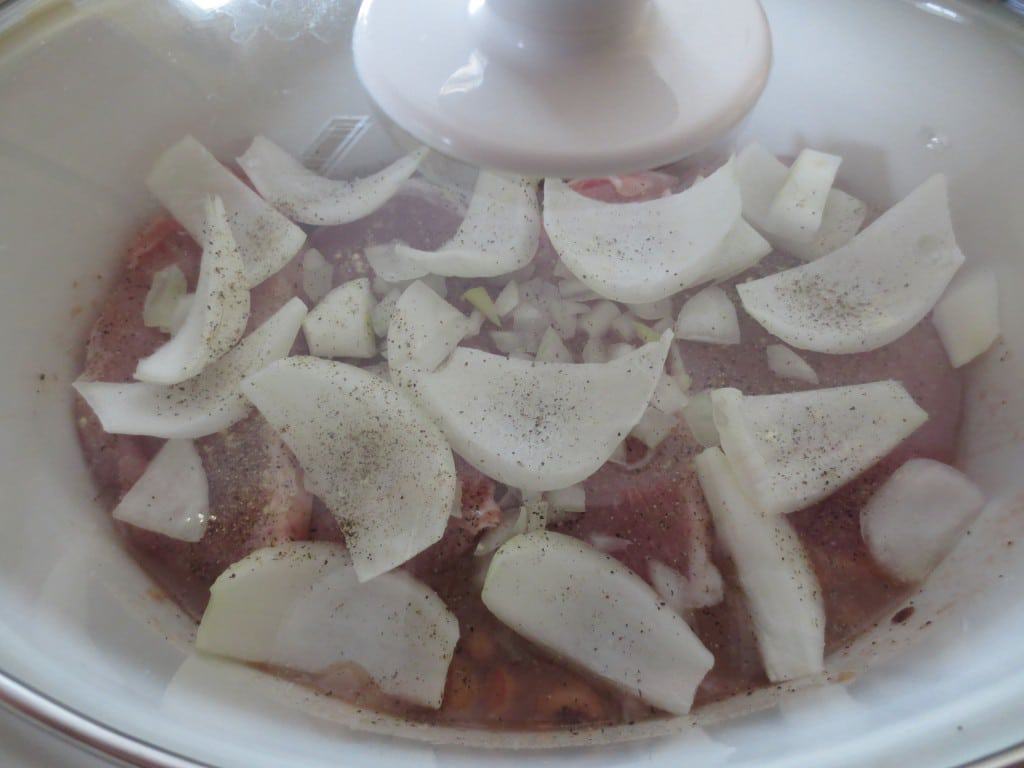 covered slow cooker with uncooked black eyed peas, onion, and pork chops