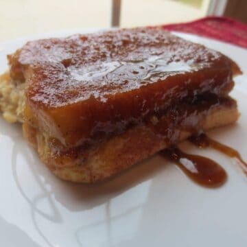 close up side view of finished french toast on white plate
