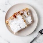 Overhead view of slices of French toast on white plate by a fork.