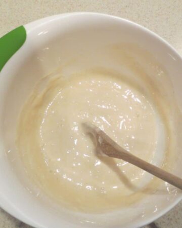Cobbler mixture in white mixing bowl with wooden spoon.