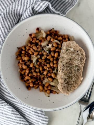 large bowl of slow cooker black eyed peas with a single pork chop next to a napkin