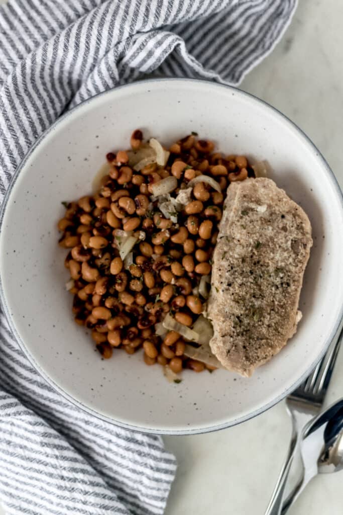 large bowl of slow cooker black eyed peas with a single pork chop next to a napkin