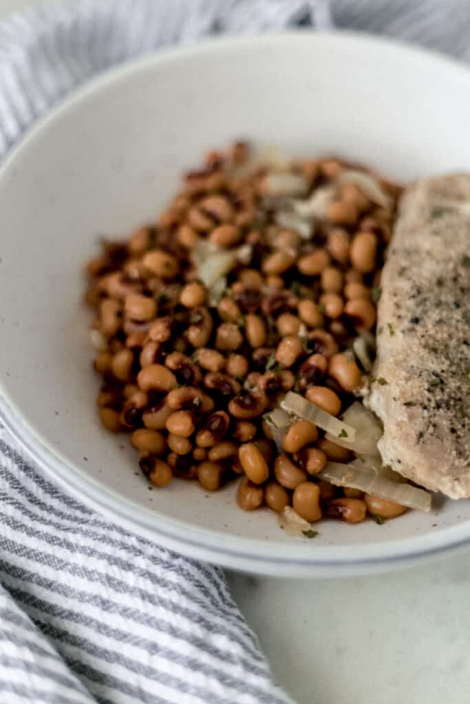 close up side view bowl of slow cooker black eyed peas and pork chop
