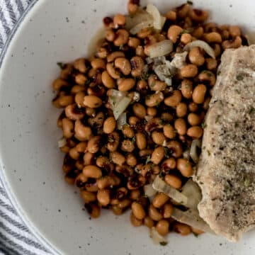 bowl with black eyed peas, onion, and a piece of pork chop