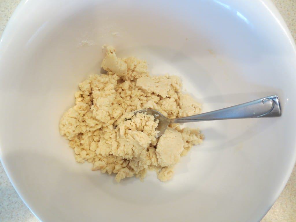 ingredients for lemon bar crust in white mixing bowl with spoon