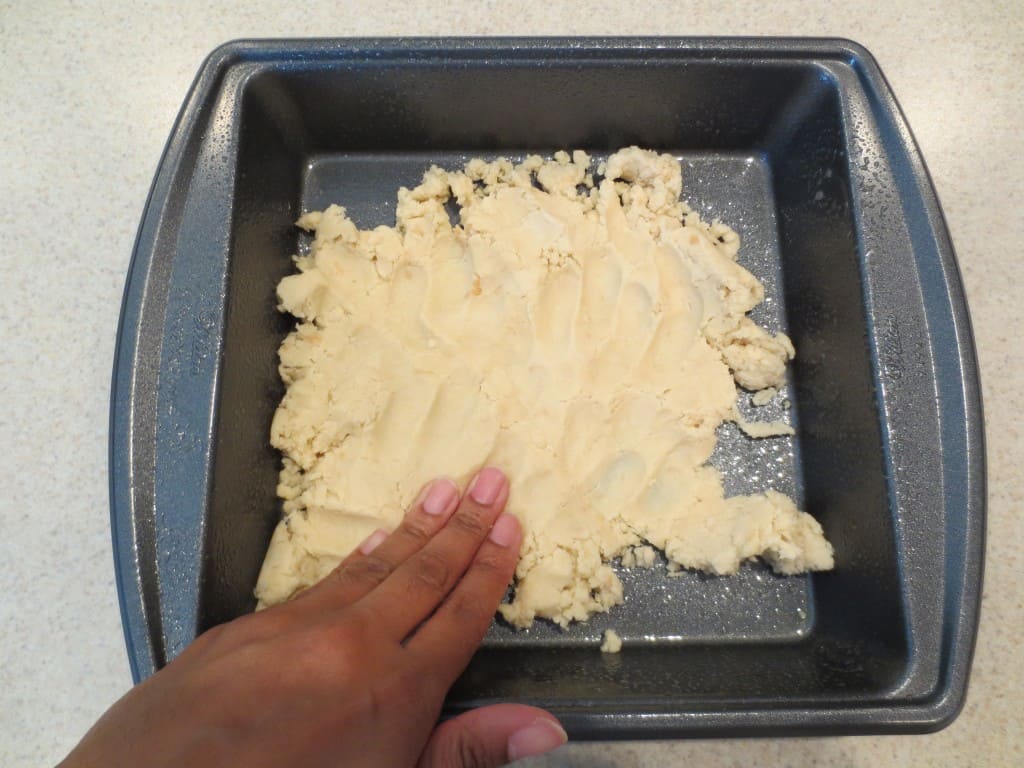 hand pressing lemon bar crust dough into square baking dish