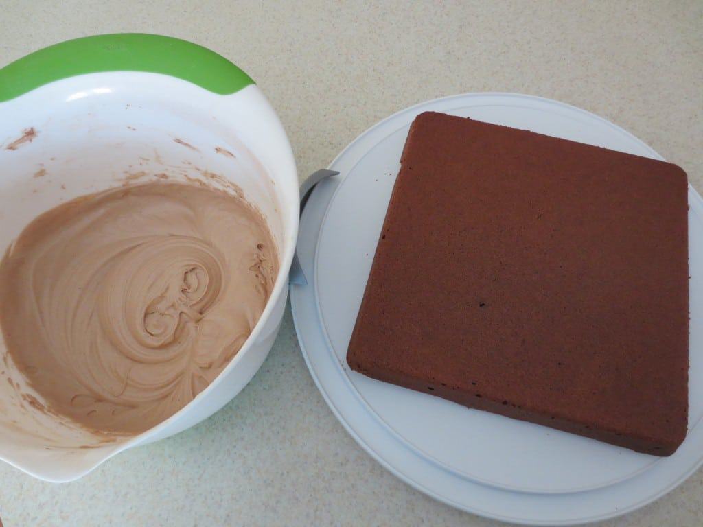 baked brownies beside bowl with frosting