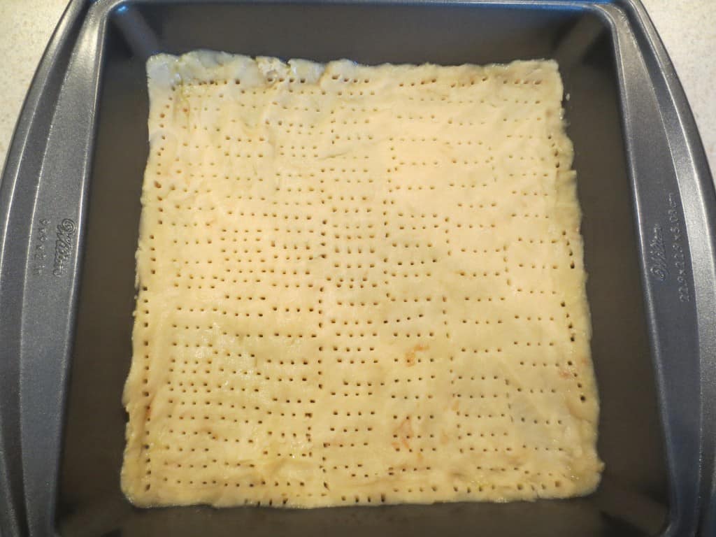 lemon bar crust pricked with fork in baking dish 