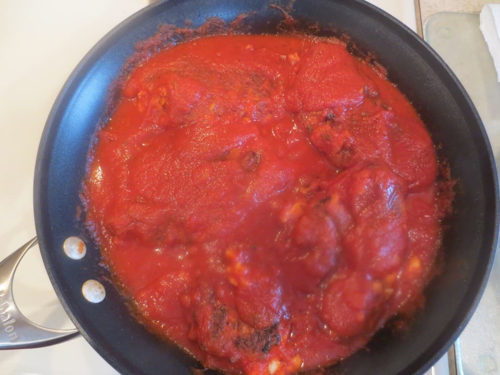 chicken in skillet topped with sauce 