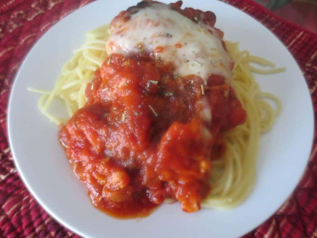 white plate with finished chicken parmesan on it