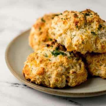 close up side view of cheddar bay biscuits stacked on a plate