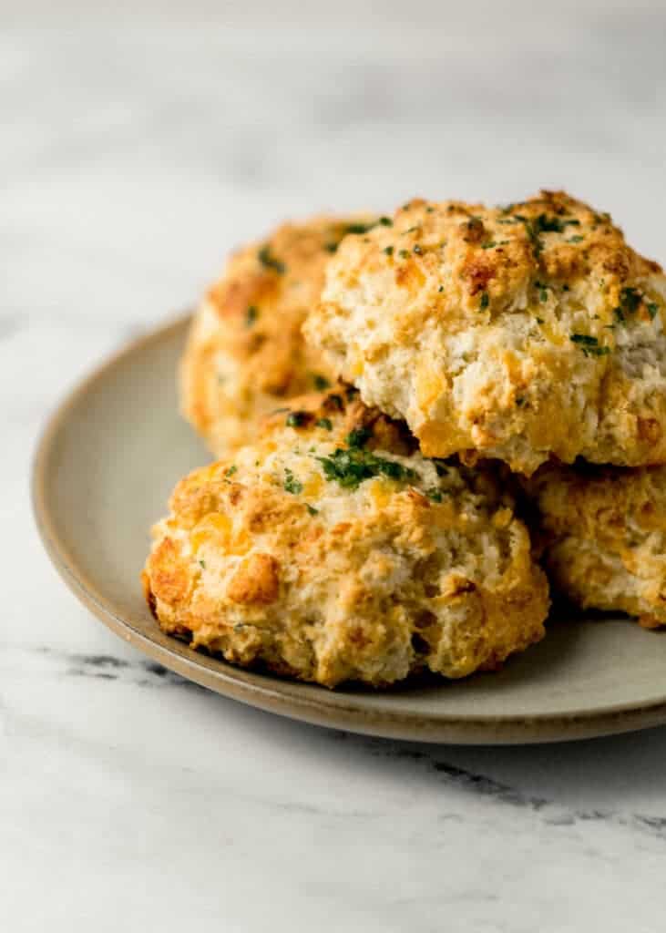 close up side view of cheddar bay biscuits stacked on a plate
