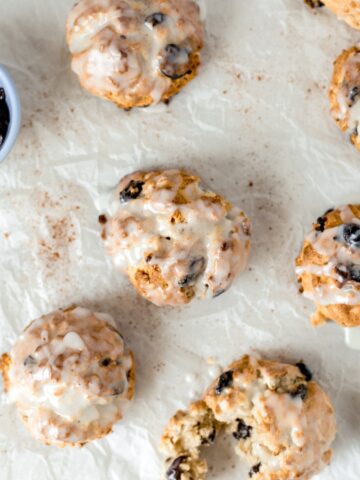 baked and glazed cherry oat scones on parchment paper