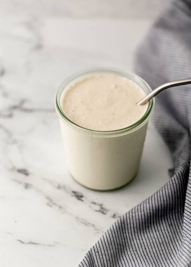 close up side view peanut butter shake in glass with straw.