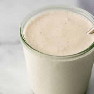 close up side view vanilla milkshake in glass jar.