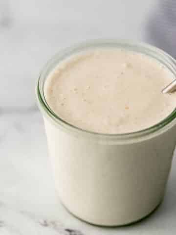 close up side view vanilla milkshake in glass jar.