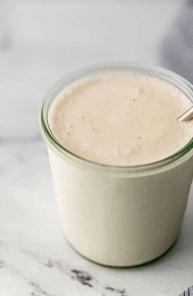 close up side view vanilla milkshake in glass jar.
