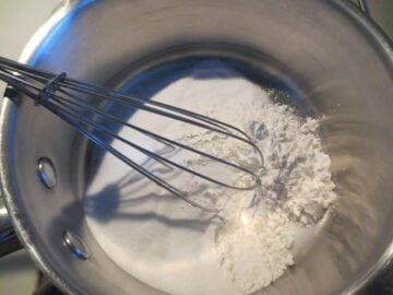 Dry ingredients in saucepan with whisk.