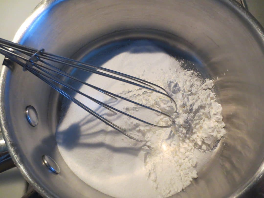 Dry ingredients in saucepan with whisk.