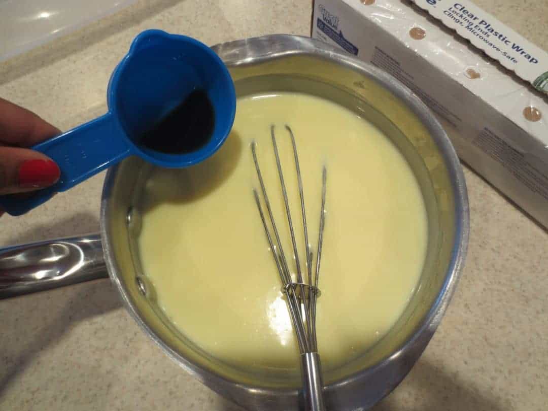 Vanilla extract added to saucepan with whisk.
