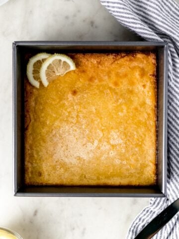 overhead view original lemon bars in a baking dish with napkin, knife, and lemon slices