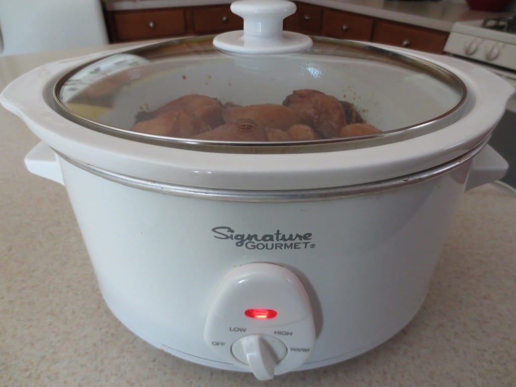 close up side view of slow cooker with chicken in it