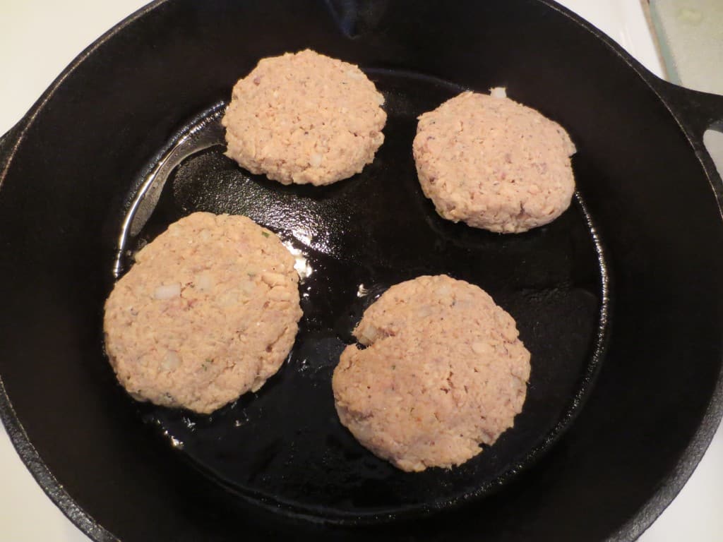 four salmon patties in a cast iron skillet