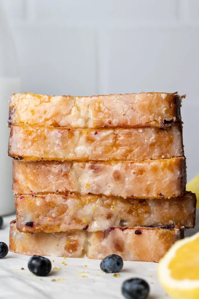 side view slices of lemon bread stacked on top of each other with lemon wedges