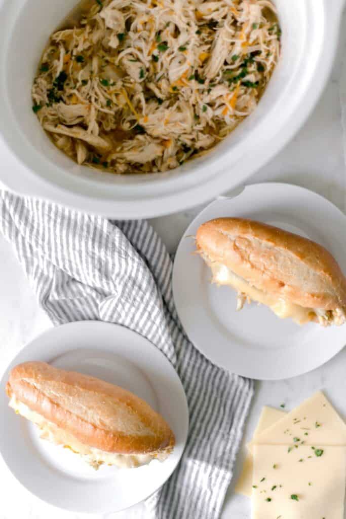 finished chicken sandwiches on white plates and in slow cooker 
