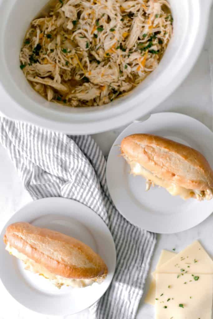 finished chicken sandwiches on white plates and in slow cooker