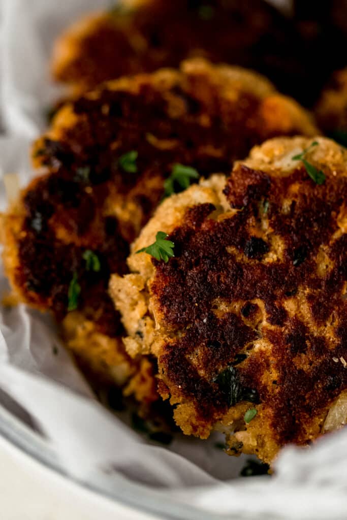 close up side view salmon patties in white bowl 
