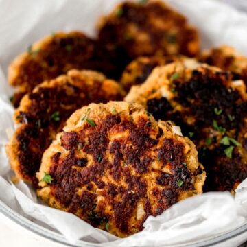 close up side view batch of cooked salmon patties in a white bowl