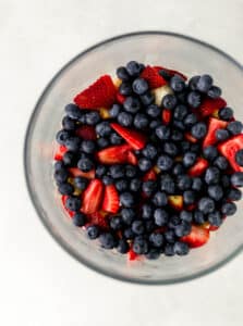 berry trifle being made in layers in glass bowl