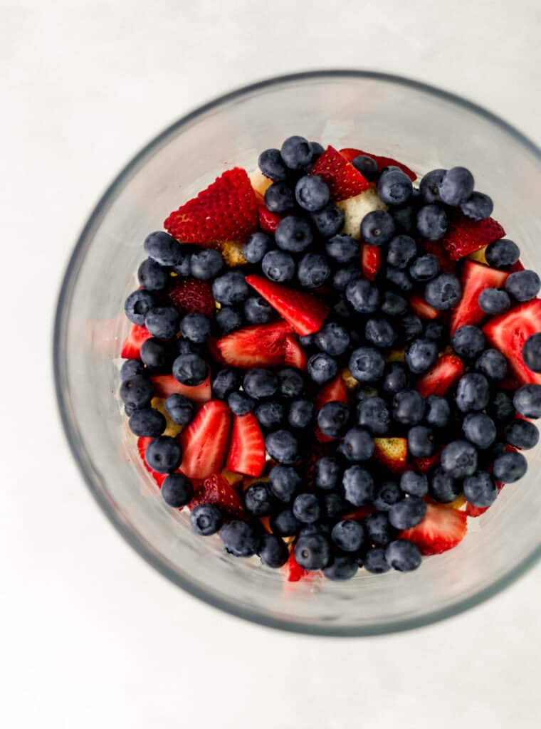 berry trifle being made in layers in glass bowl
