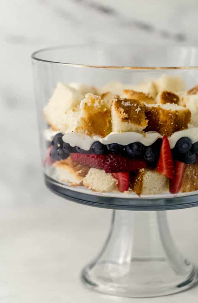 side view of glass trifle bowl with ingredients being layered. 