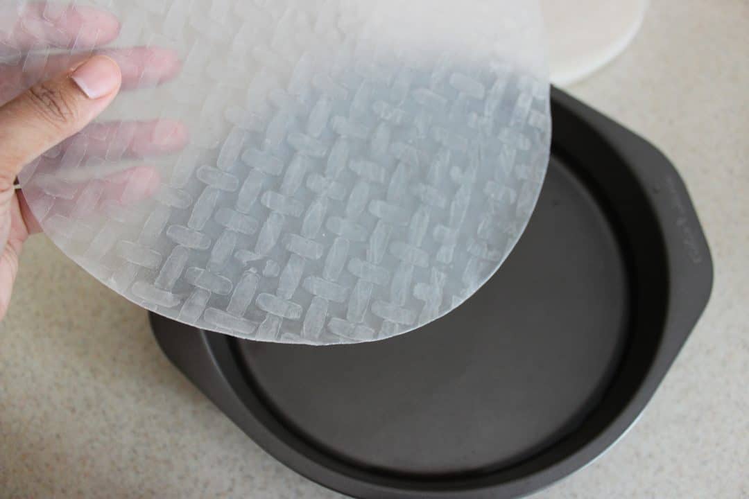 hand placing rice paper in baking pan with water in it