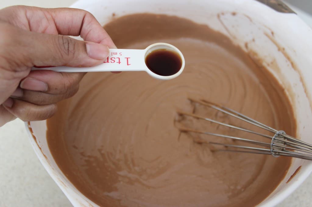 Close-up of vanilla extreact being added to Chocolate Sour Cream Pound Cake mixture in bowl with whisk