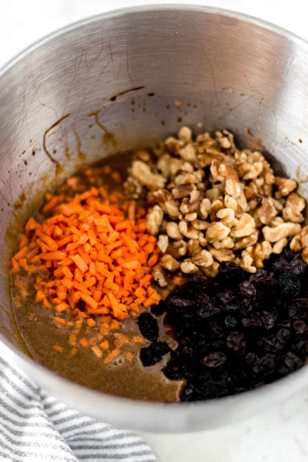 ingredients for carrot raisin nut bread in a silver mixing bowl