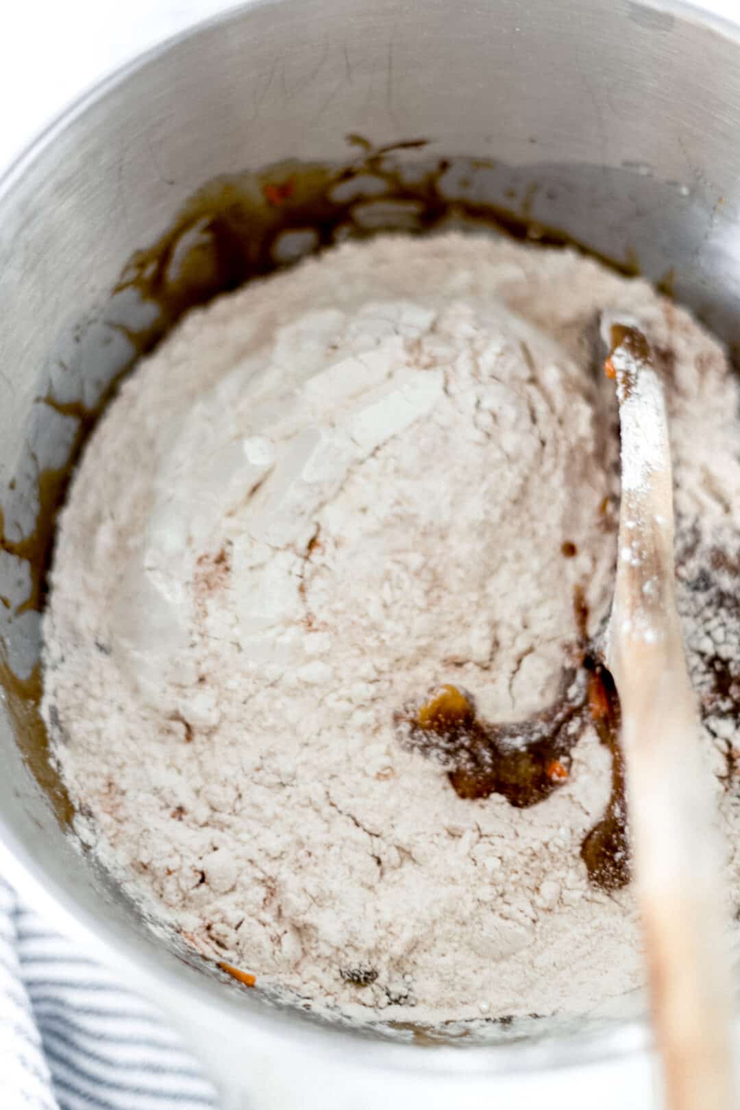 dry mixture added to carrot raisin bread batter with wooden spoon