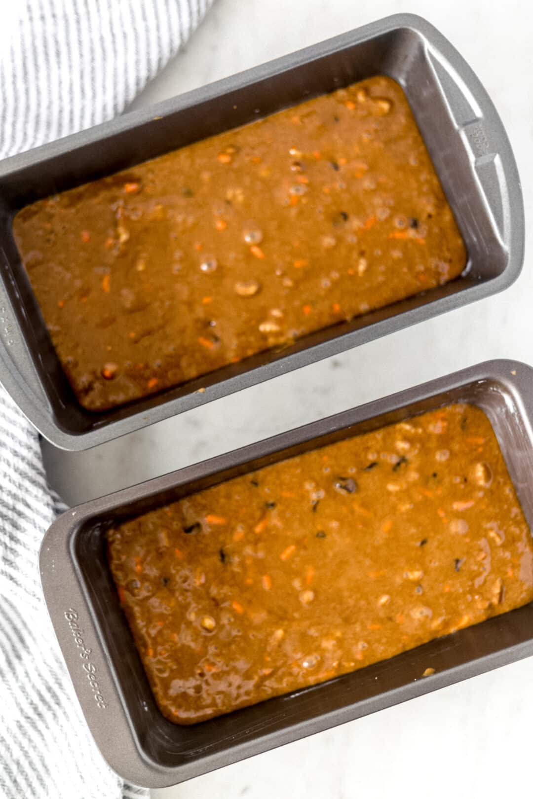 uncooked carrot raisin bread poured into two loaf pans for baking