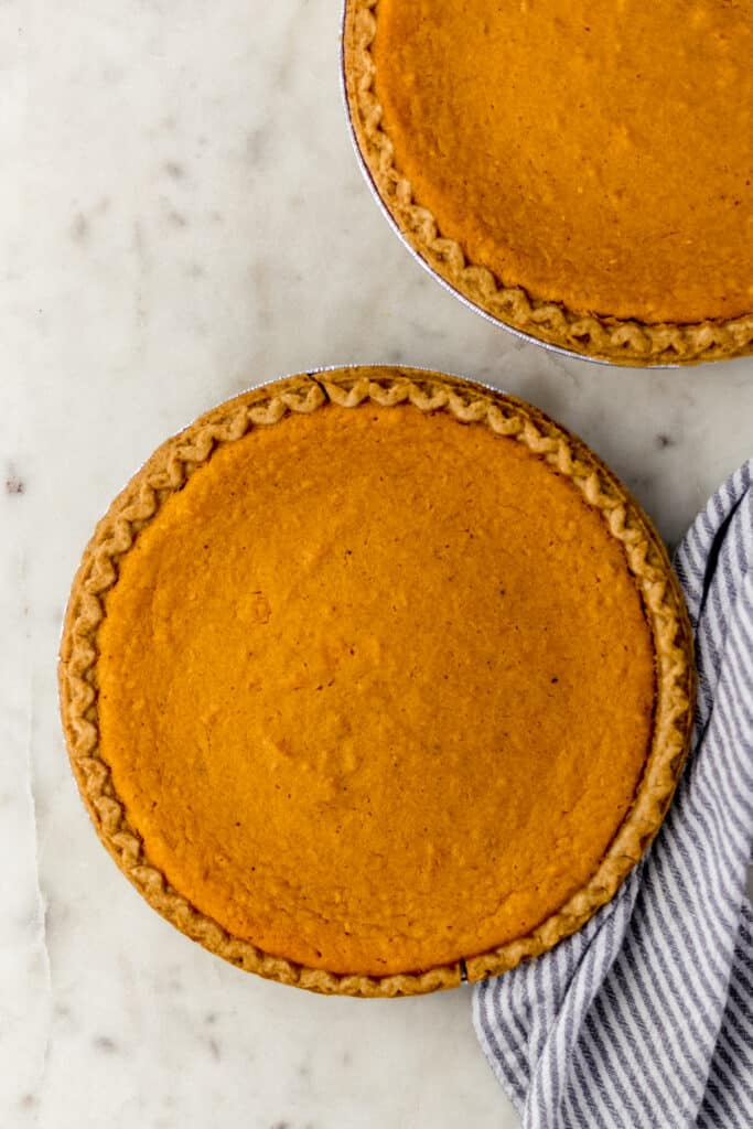 overhead view of two freshly baked sweet potato pies on marble surface