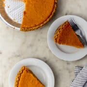 overhead view of cut sweet potato pie with two slice on two white plates.