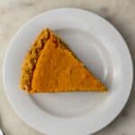 overhead view slice of sweet potato pie on white plate next to fork.