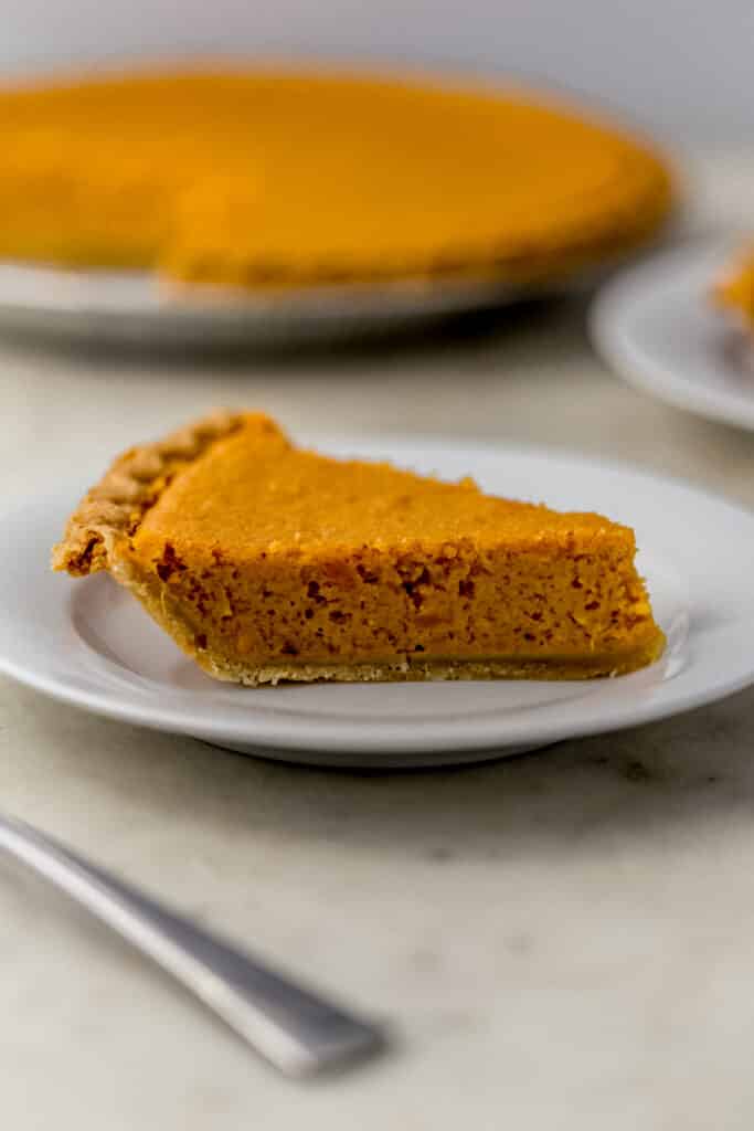 close up side view slice sweet potato pie on white plate