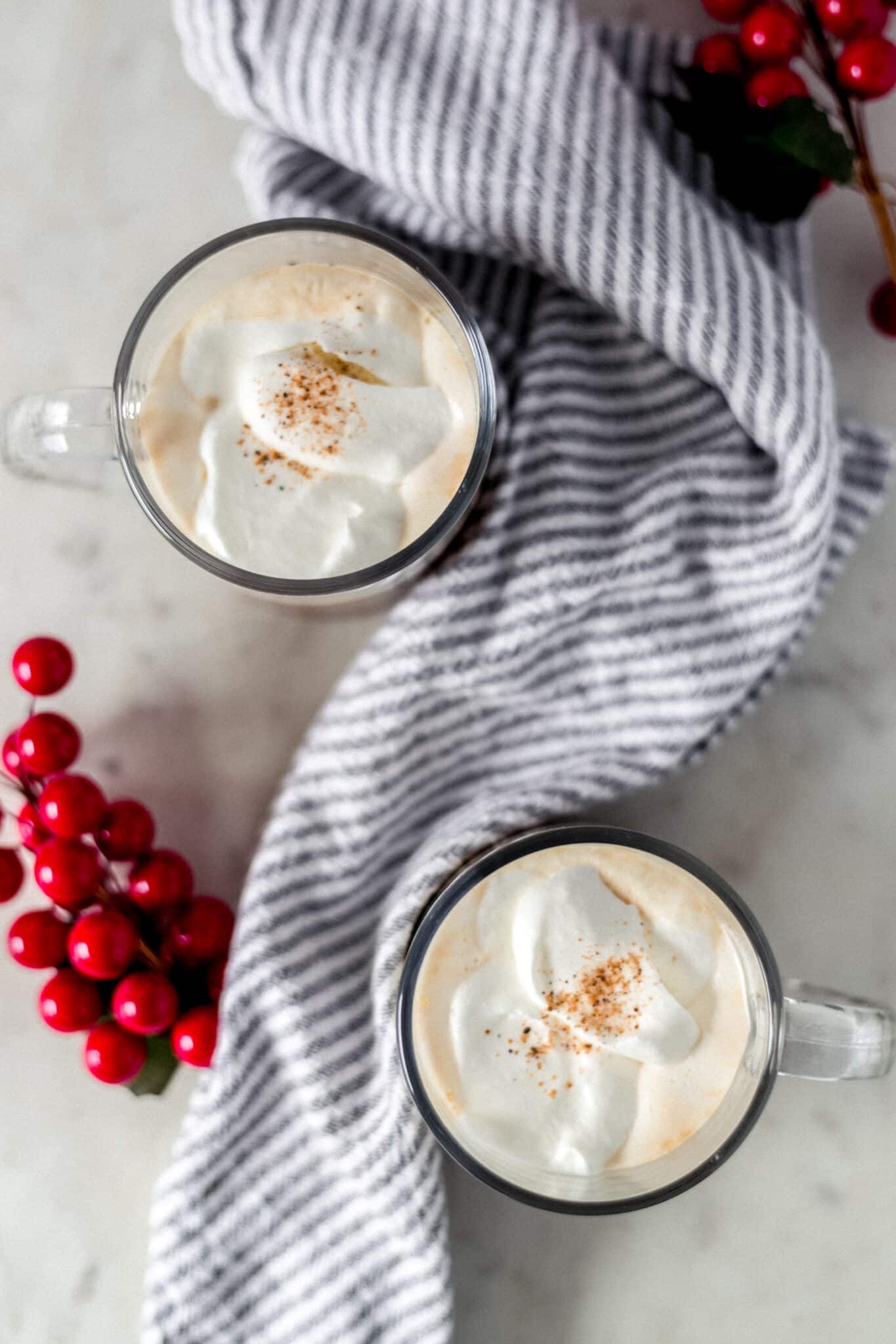 gingerbread latte in two mugs with a napkin and cranberries