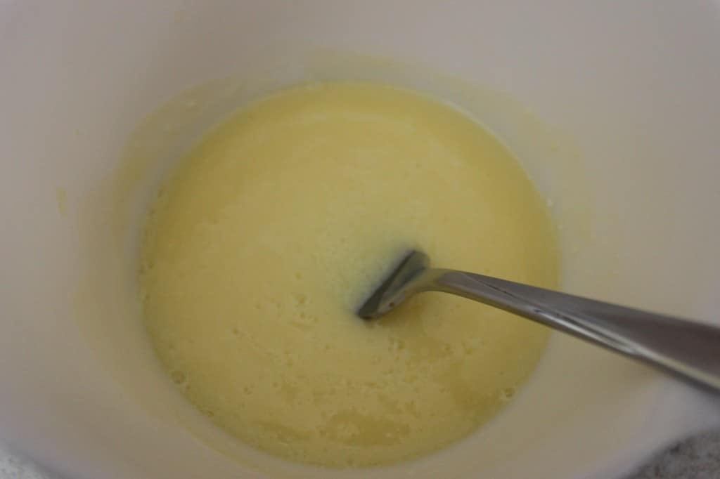 milk, melted butter, and egg in white mixing bowl with fork